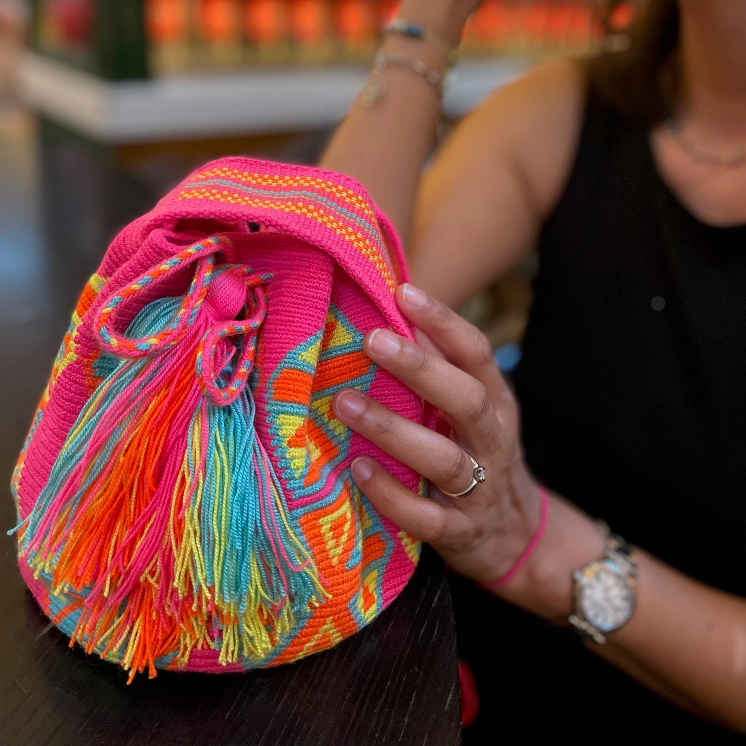 femme qui tient un sac en crochet mochila de couleur rose bleu vert et orange